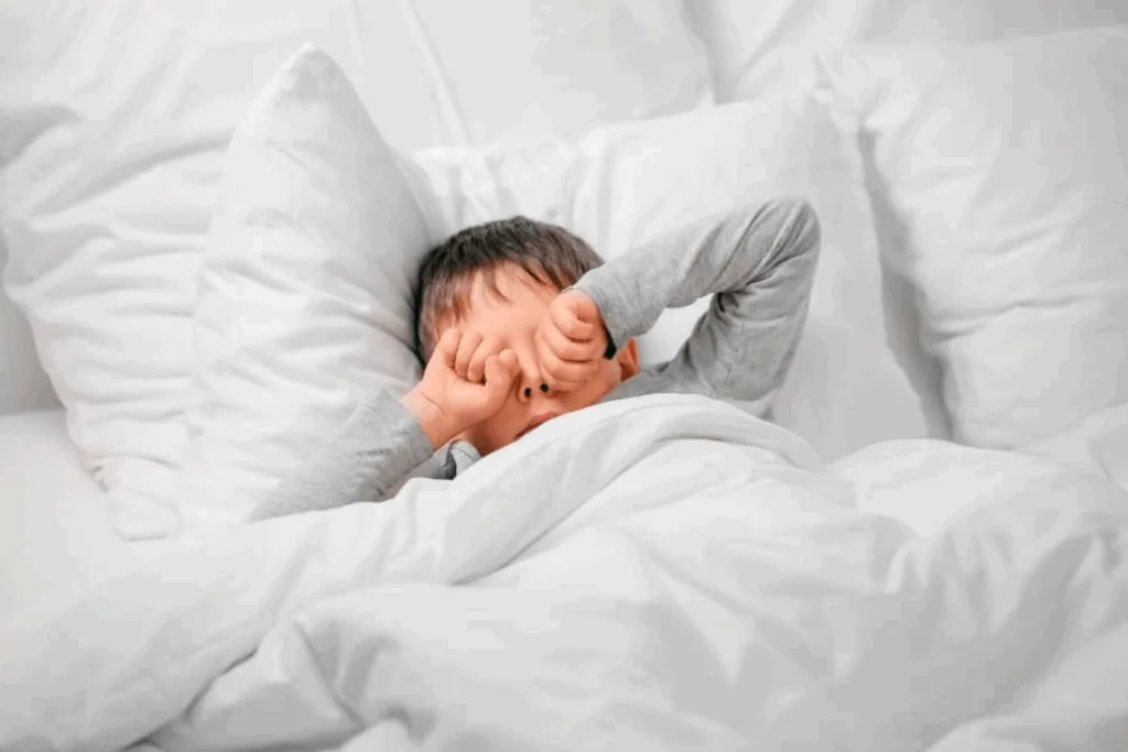 Niño despertando en la cama, reflejando la importancia del descanso para recuperar la rutina diaria